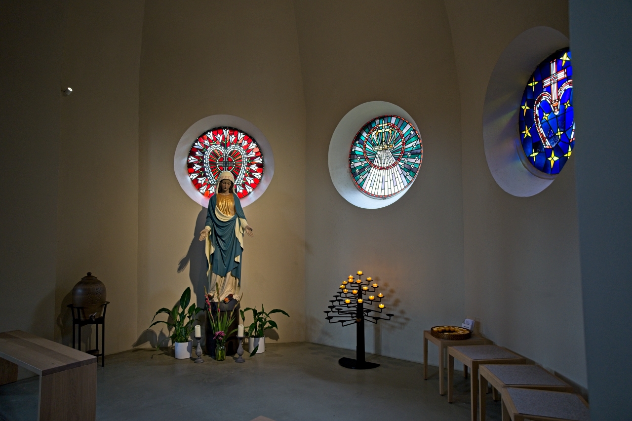 Marienstatue und runde Buntglasfenster in Kirche